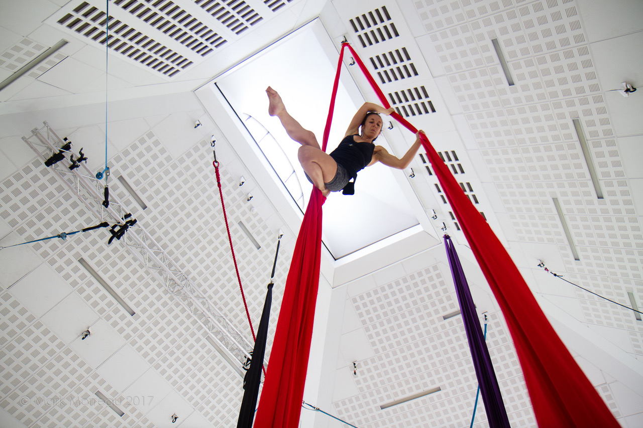 Female aerial performer hanging from silks in the Creation Space