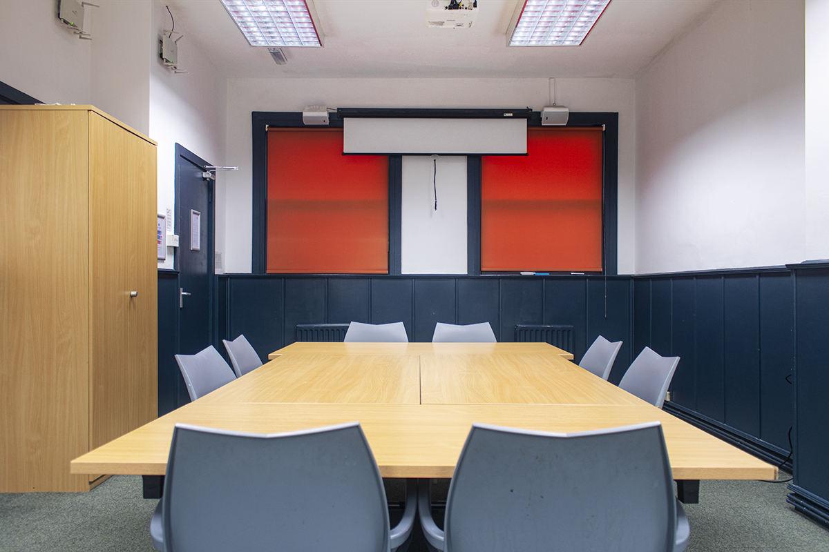 Irving Room in boardroom set-up with desks, chairs and projector screen